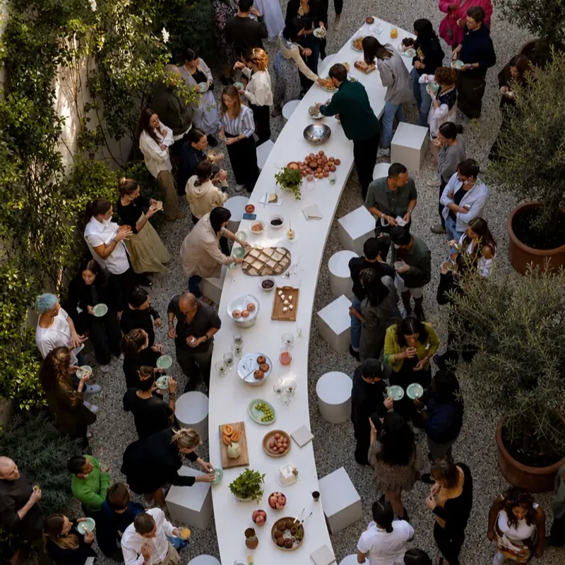 Vista aérea de una activación de marca: una mesa larga y curva con comida, rodeada de gente